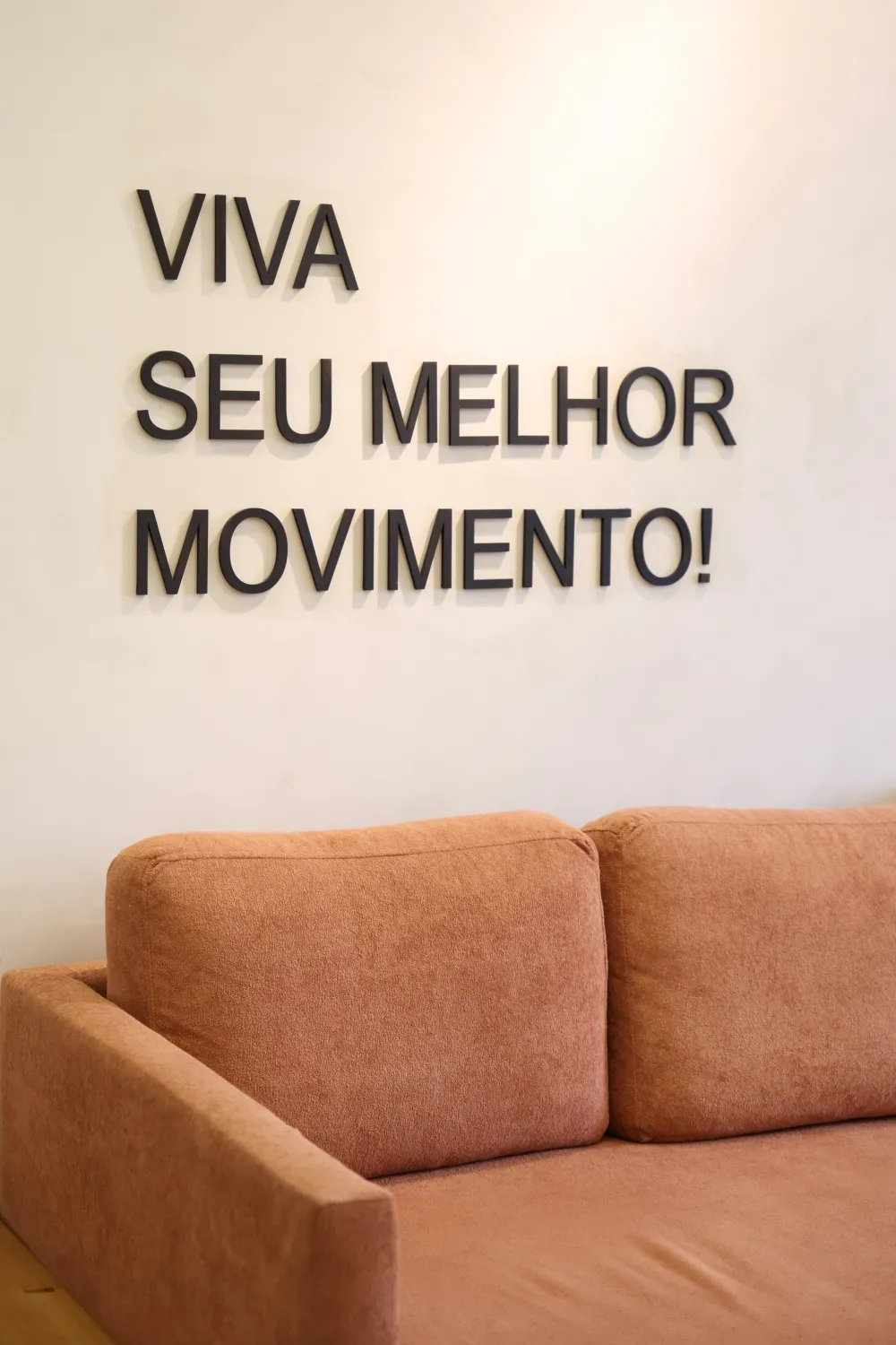 Recepção com sofá e a frase Viva seu melhor movimento na parede